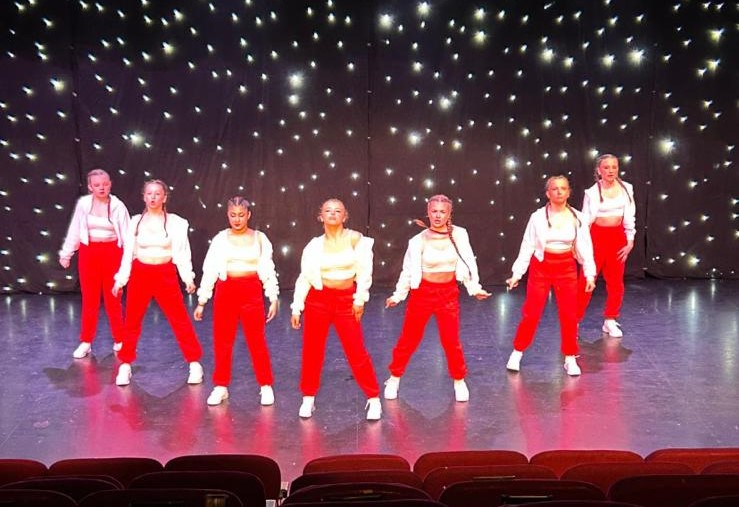 Smiling children waving on stage after their performance